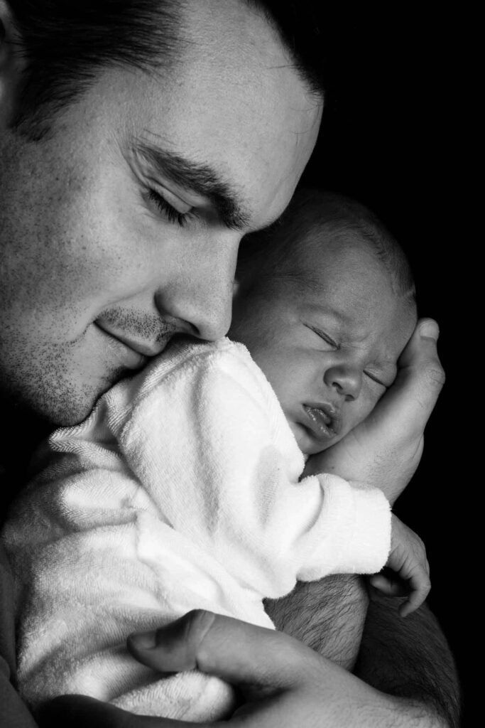 Un padre cargando a su hijo recién nacido contra su pecho
